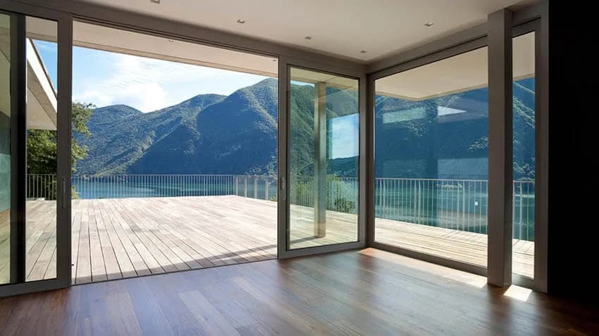 Floor-to-ceiling aluminium sliding glass doors on a mountain-view terrace