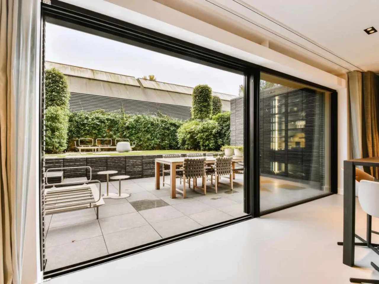 Slim sliding door opened from a dining room onto a courtyard with timber decking