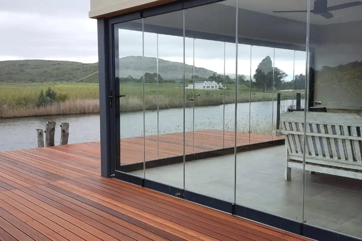 Frameless glass panels enclosing a timber terrace by the water