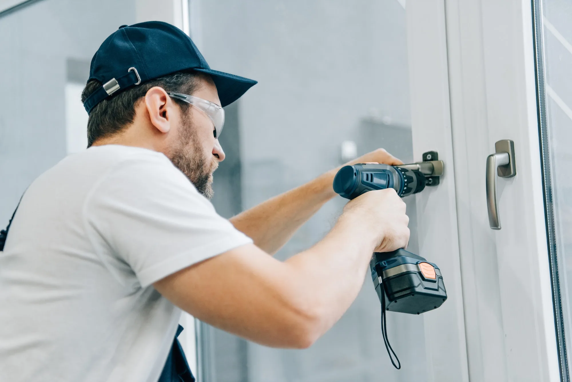 Installer fitting a window handle with a drill