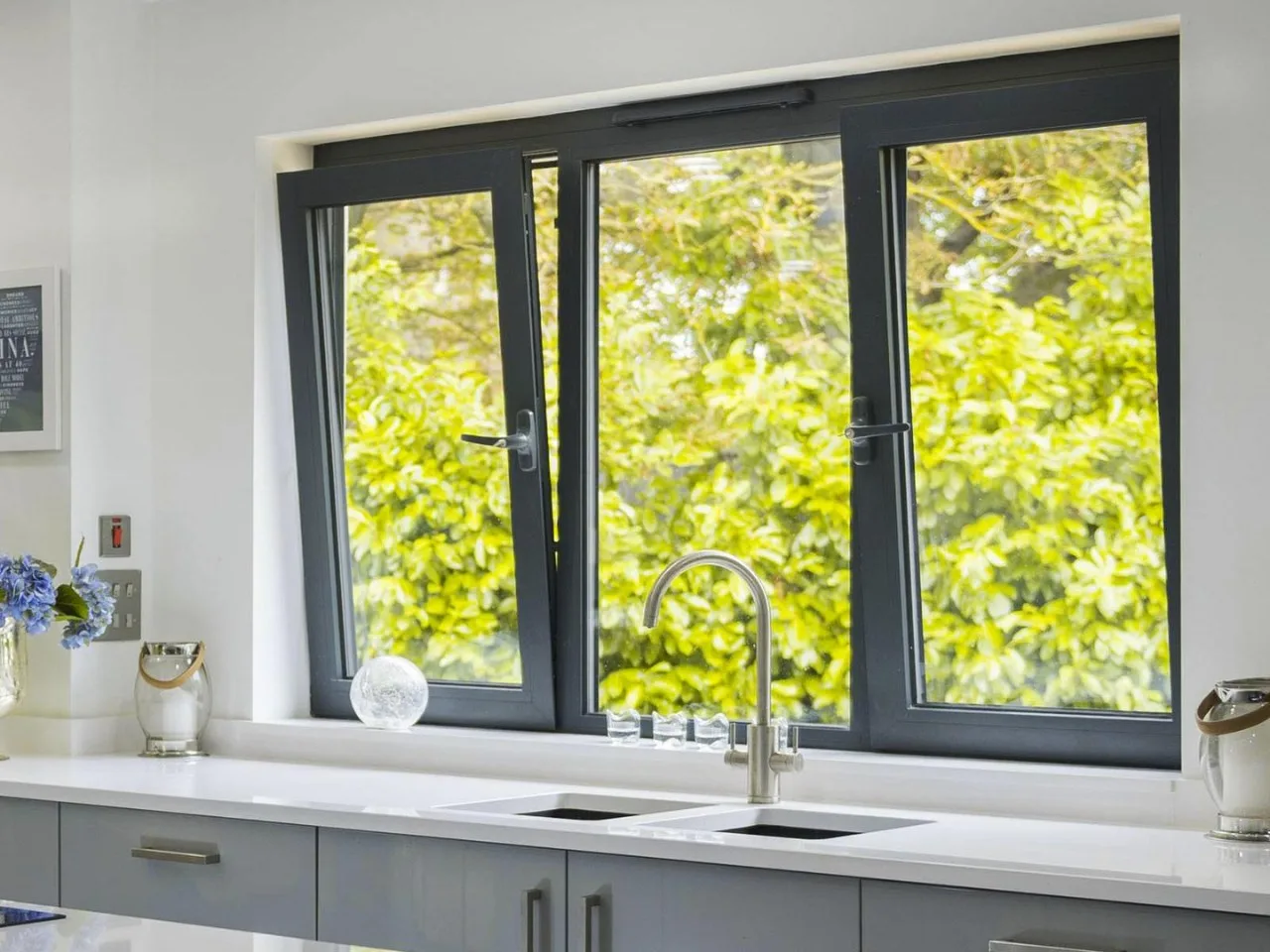 Grey aluminium casement window above a kitchen sink
