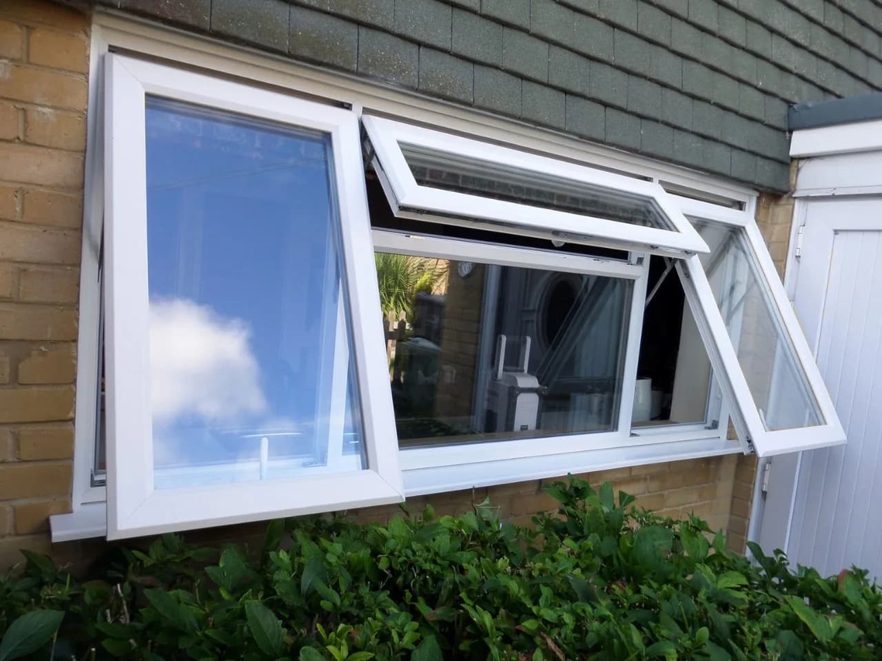 Top-hung aluminium window open on a brick house